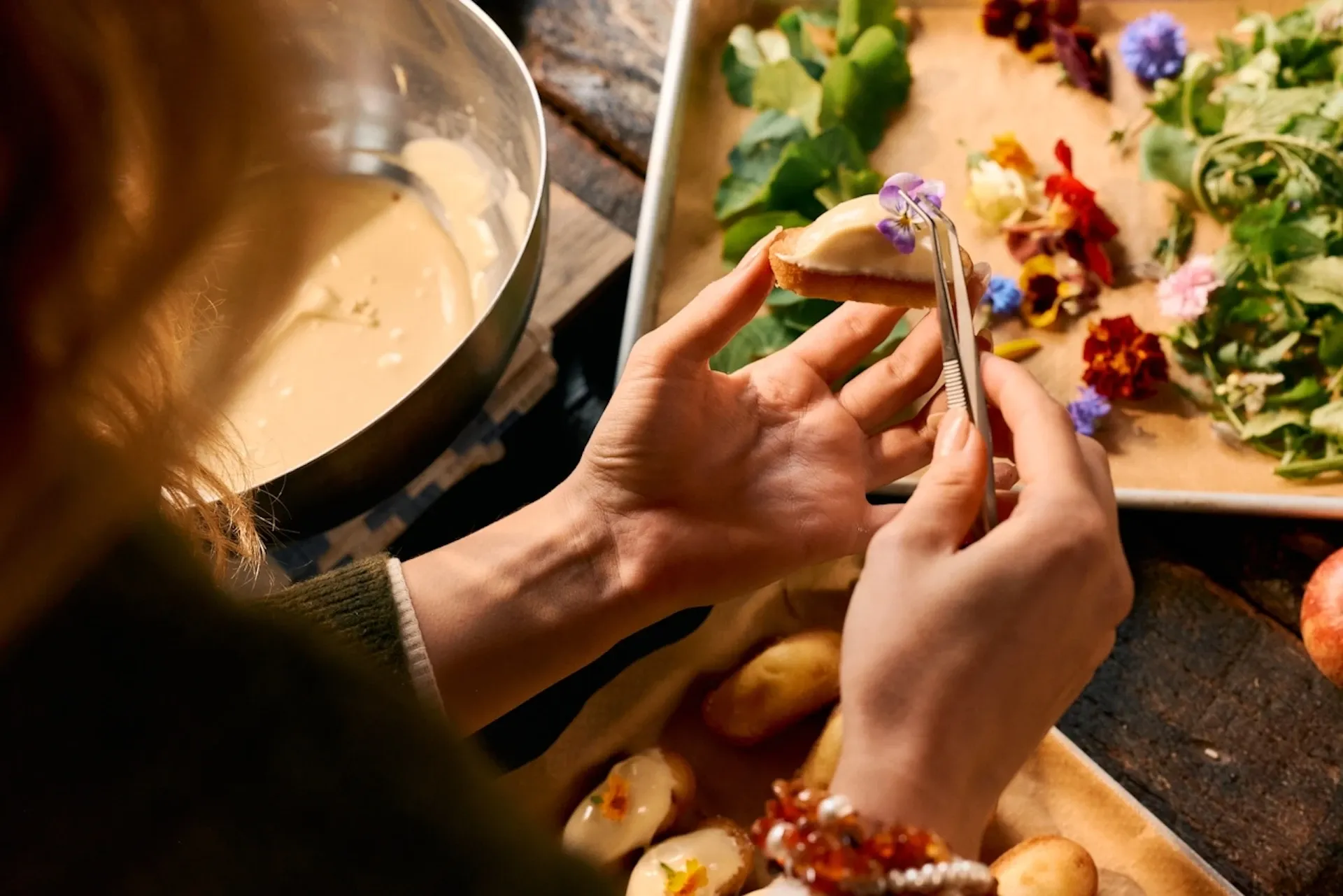 Person placing a small flower on a cake with a pair of tweezers