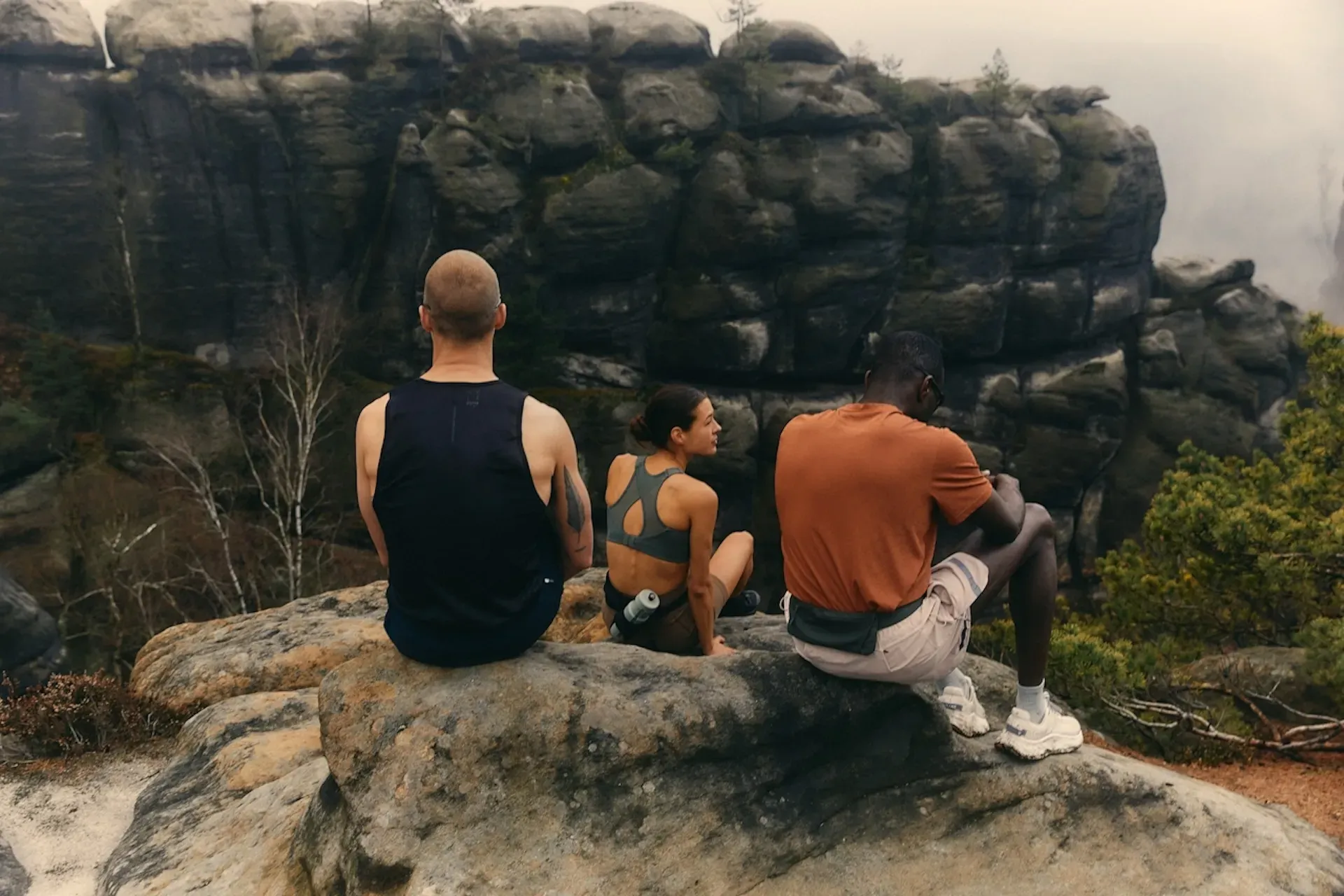 Three friends sitting on a rock in the mountains