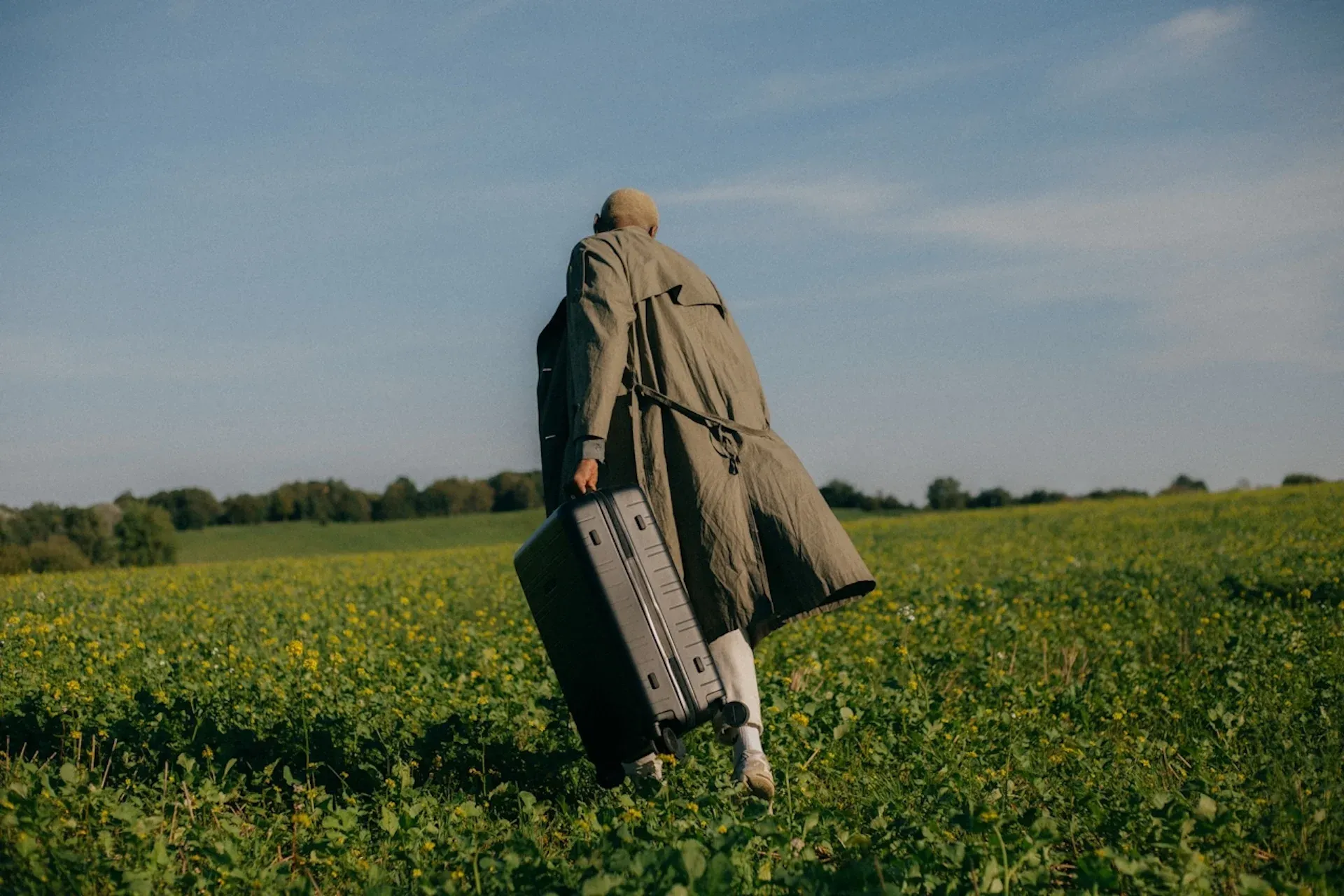 A man with a suitcase walking through a field