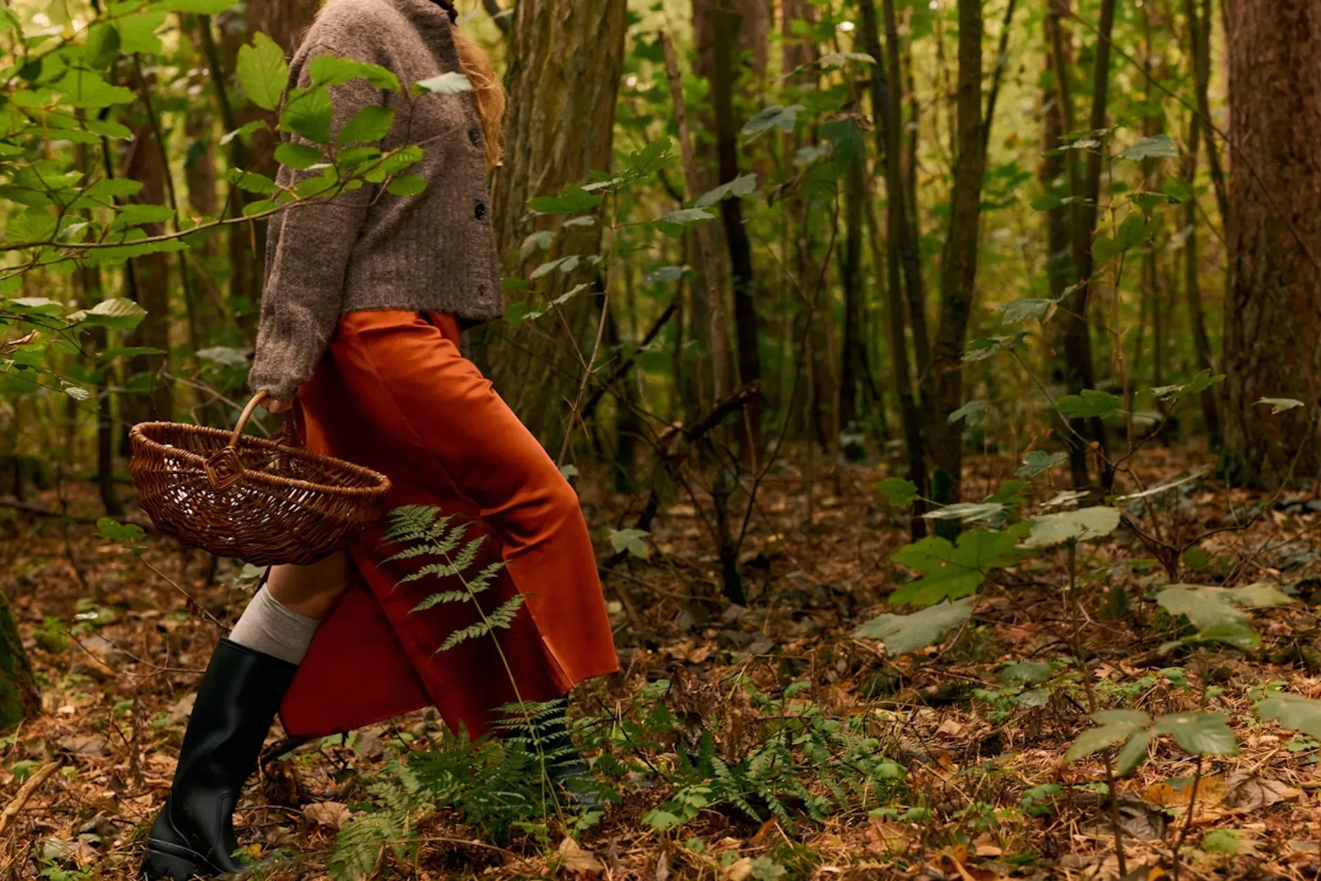 A person walking through the woods with a basket