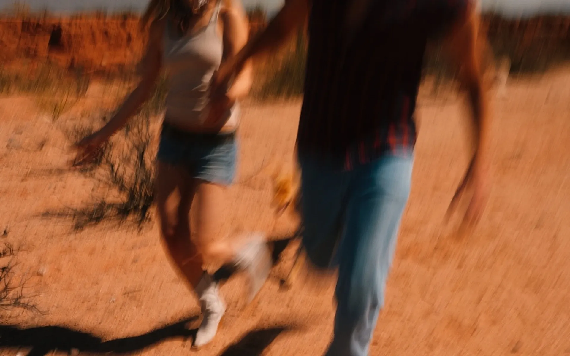 Two people holding hands and running through the desert