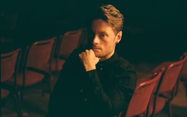 A photo of Christoffer Moe Ditlevsen, sitting on a red chair. Photo by Sune Chee.